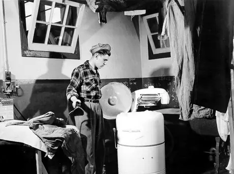 A young man irons and checks a wash in the YMCA laundry facilities