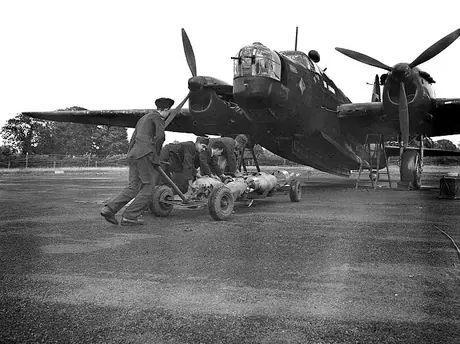 Bombs are wheeled out to be loaded underneath an RCAF bomber