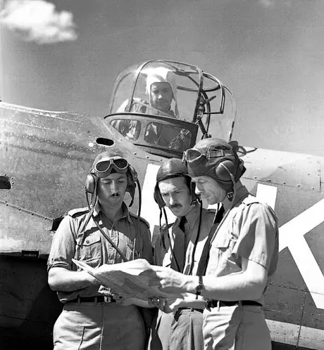 An aircrew in front of a Bolingbroke bomber gun turret