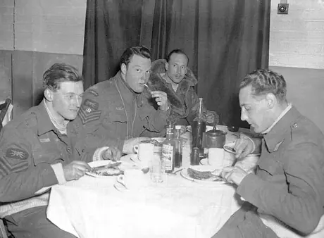 Four aircrew eating a breakfast of bacon and eggs after returning from night raids