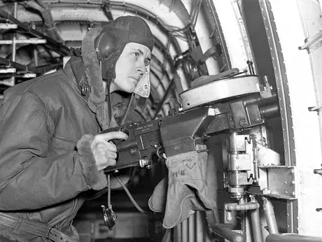 An Air Gunner at the side gun of a four-engine bomber at a Royal Canadian Air Force Bomber Squadron
