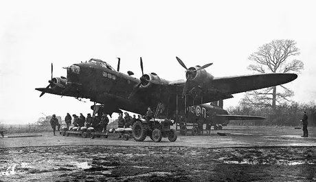 Members of an RCAF Stirling Bomber Squadron crew stand behind bombs brought for loading into a Stirling