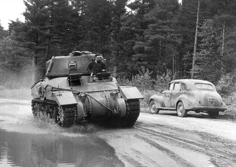 A tank belonging to the Armoured Corps passes a car