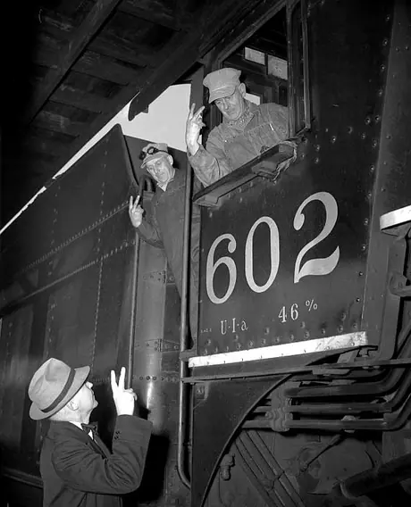 Elmer Davis and two Central Vermont Railway crew exchange the victory sign