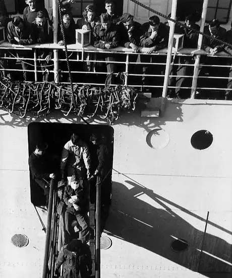 Soldier is carried off the hospital ship RMS Lady Nelson on a stretcher as soldiers and staff watch