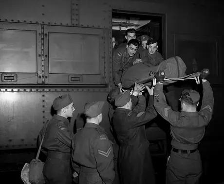 Private B.T. Parton is transported on a stretcher from a hospital train to a waiting ambulance