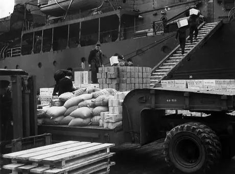 Crew members of the auxiliary cruiser HMCS Prince David, previously a luxury liner, load supplies