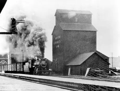 Canadian Northern Railway steam locomotive and freight train at elevator