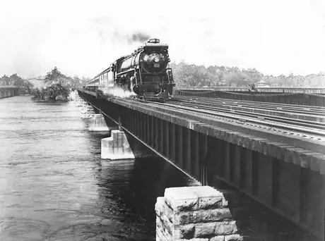 Canadian National Railways steam locomotive no. 6030 hauls the International Limited passenger train across a bridge