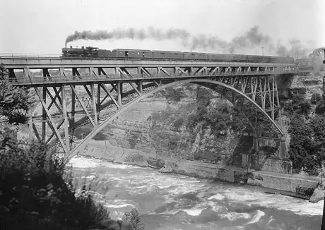 Canadian National Railways Pacific type locomotive hauls passenger train across a bridge across the Niagara River from New York to Canada
