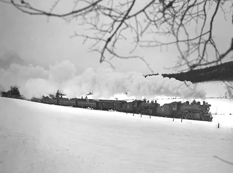 Two Canadian National Railways steam locomotives are needed to haul a passenger train through the snow covered mountains
