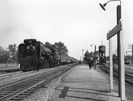 A Canadian National Railways passenger train hauled by steam locomotive no. 6233 takes on baggage and supplies at a railway station