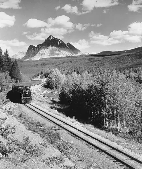 A Canadian National Railways passenger train steams through the foothills of the Rockies