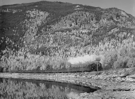 A Canadian National Railways passenger train along the shore of a mountain lake