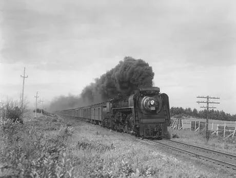 Canadian National Railways steam locomotive no. 6211 hauls a passenger train through rural Québec