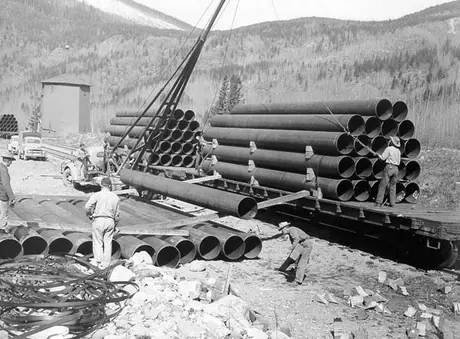 Workers unloading sections of pipe for the Trans Mountain Pipeline