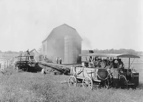 A steam tractor powers a threshing machine