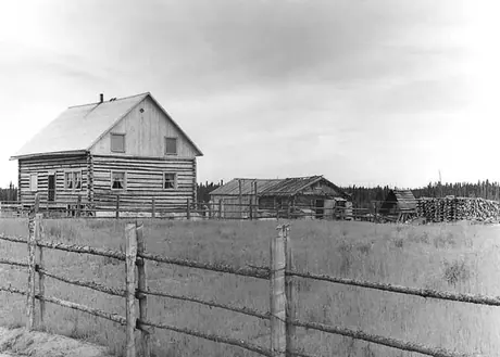 A log house and farm buildings