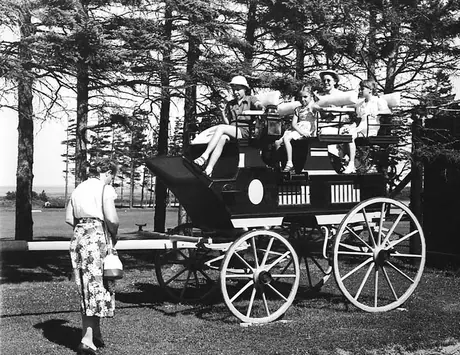 Visitors pose for the camera aboard a stage coach on display in a park
