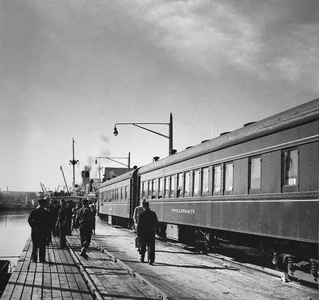 A passenger train and steam ship at the dock