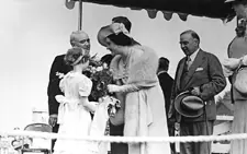 Her Majesty Queen Elizabeth receives a bouquet of flowers as the Mayor of Stratford speaks with King George VI and Prime Minister King looks on