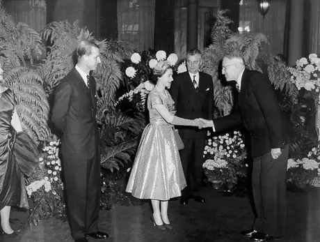 Queen Elizabeth, standing between Prince Philip and Prime Minister of Canada John Diefenbaker, greets a guest during an official reception