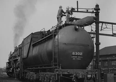 Workers fill the water tank of Canadian National Railway steam locomotive no. 6302