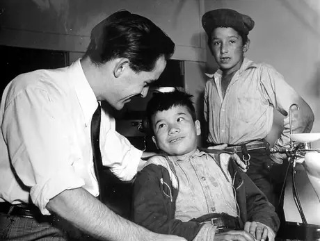 Dentist Alex Mclean preparing to examine a young boy named Ivan for dental work