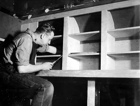 H.E. Thorne, carman, fitting kitchen cupboards in the dental car