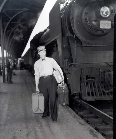 Red cap with luggage next to a steam train, Bonaventure station