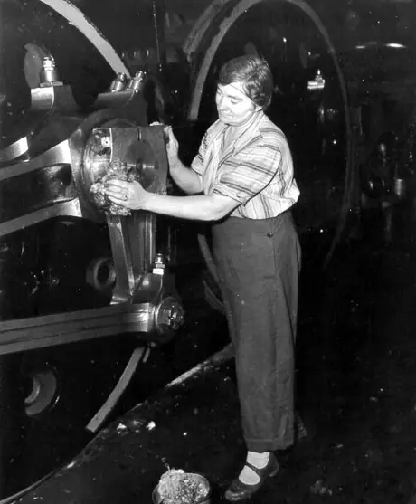 CN employee cleaning the driving wheels of a steam locomotive