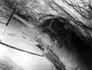 An electric long-wall cutter biting into pure salt while the electric drill bores holes for dynamite sticks, miners work in a 50 degree angle