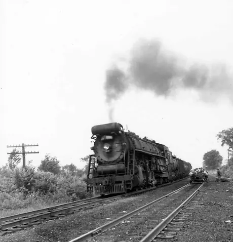 A Central Vermont Railway freight train headed by T-3-a steam locomotive 707 passes a track work site.