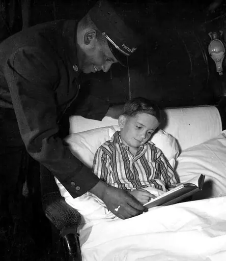 A porter checking on a child in the sleeping car