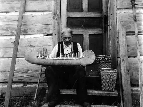 Ojibway Elder crafting a model of a birch bark canoe at Sheedy Camp, French River