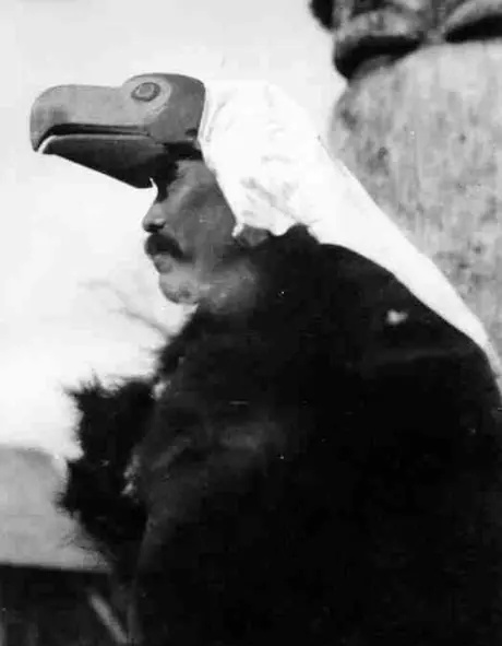 Kitwanga man wearing eagle headdress with white cloth veil and a fur cape.
Original caption: