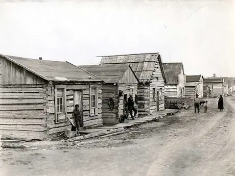 Aboriginal villagers outside a row of wooden homes.
Original caption:
