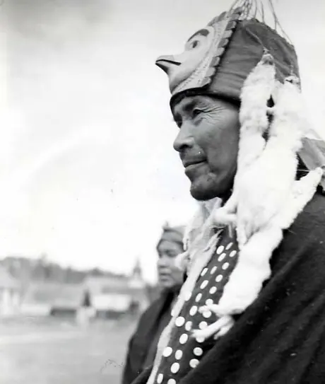 Wet'suwet'en man wearing bird head piece with ermineskin fringe and button blanket.
Original caption: