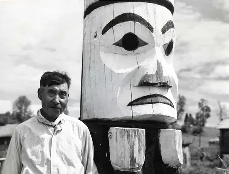 Donald Gray in front of aged, painted totem pole.
Original caption: