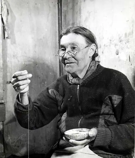 Elderly Kimsquit woman sewing beadwork on moosehide jacket.
Original caption: