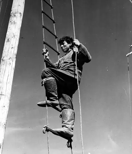 Young Inuk man climbing a rope ladder.
Original caption: