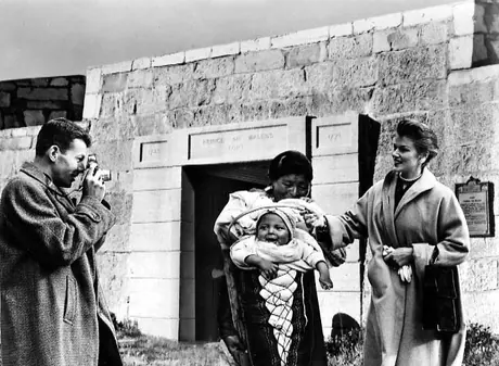 Tourists photographing Cree mother with baby in cradleboard at Ft. Prince of Wales