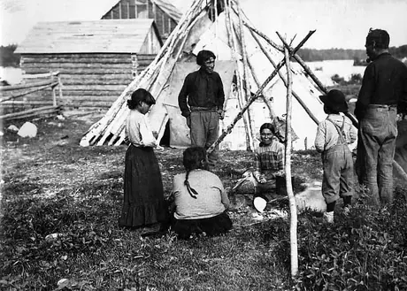 Ojibwa family gathered around a campfire preparing a meal