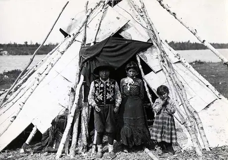 Ojibwa boy and two grils at the entrance to their birch bark wigwam. 
Original caption: