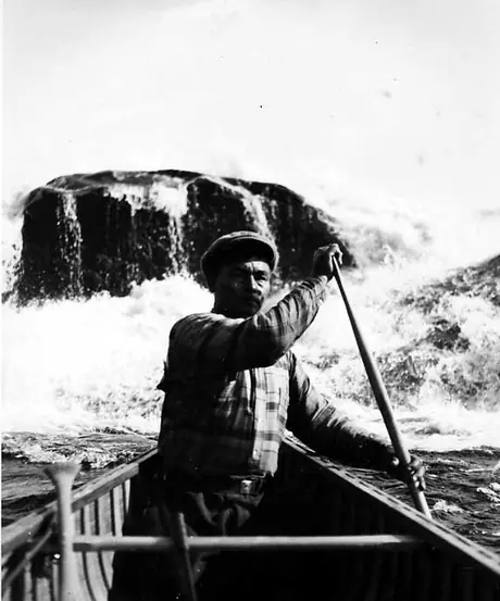 Cree man paddling in rough rapids.
Original caption: