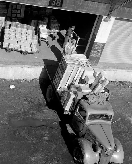 Motorman and station agent loading boxes of fruit onto freight truck
