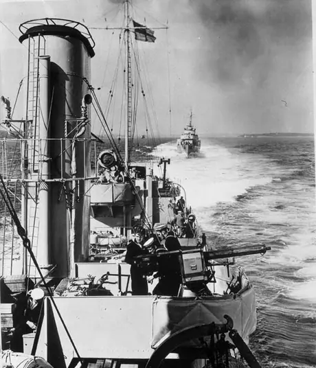 Canadian destroyers in line astern; steam out to sea to take up their positions in convoy