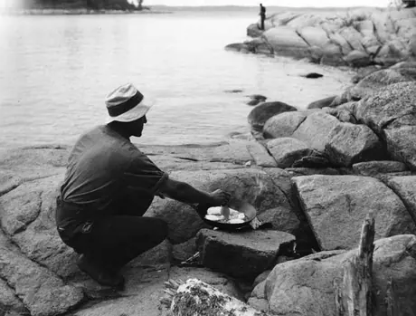 Man cooking fish over a campfire