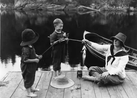 Children displaying their catch to a woman