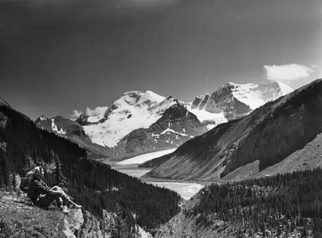 A hiker resting near the Columbia Icefield Motor Road, with the Athabasca Glacier in the background, Jasper
